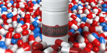 Eine Pillendose mit der Aufschrift „Doping“ und zahlreichen Tabletten davor